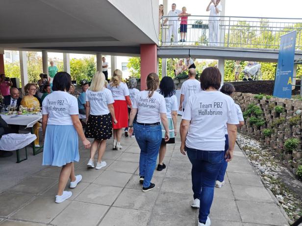 Eine Gruppe von Frauen mit T-Shirts „Team PBZ Hollabrunn“ geht auf einem Platz.