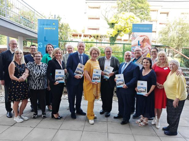 Eine Gruppe von Menschen posiert mit Broschüren zum 30-jährigen Jubiläum des PBZ Hollabrunn.
