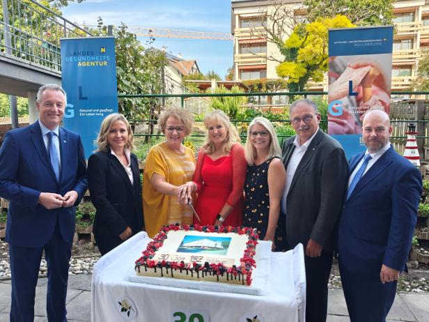 Eine Gruppe von Personen steht um eine Torte zum 30-jährigen Jubiläum des PBZ Hollabrunn.