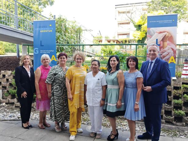 Eine Gruppe von Menschen posiert vor Bannern des Landesgesundheitsagentur NÖ Pflege- und Betreuungszentrum Hollabrunn.