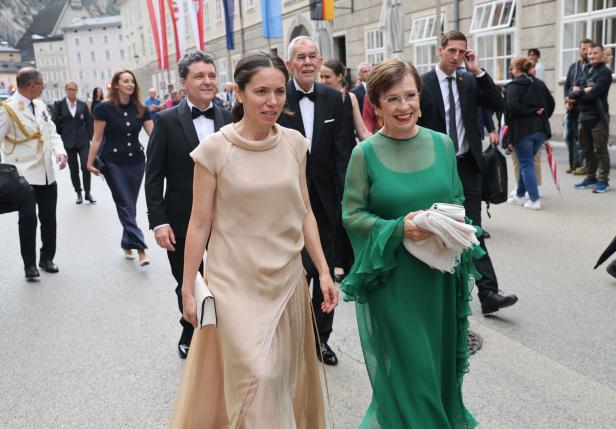Frauen in Abendkleidern gehen eine Straße entlang.