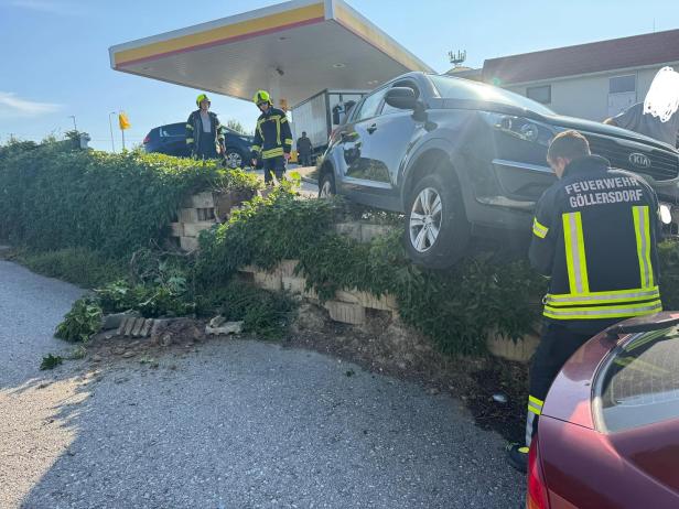 Ein Auto ist an einer Tankstelle über eine Mauer gefahren.