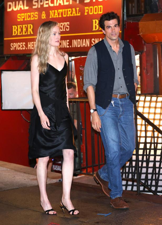 Eine Frau in einem schwarzen Kleid und ein Mann in Jeans gehen in New York die Straße entlang.