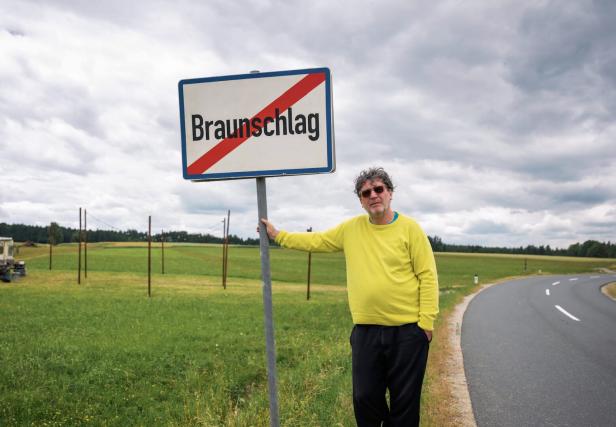 Ein Mann steht an einem Ortsschild von Braunschlag, das durchgestrichen ist.