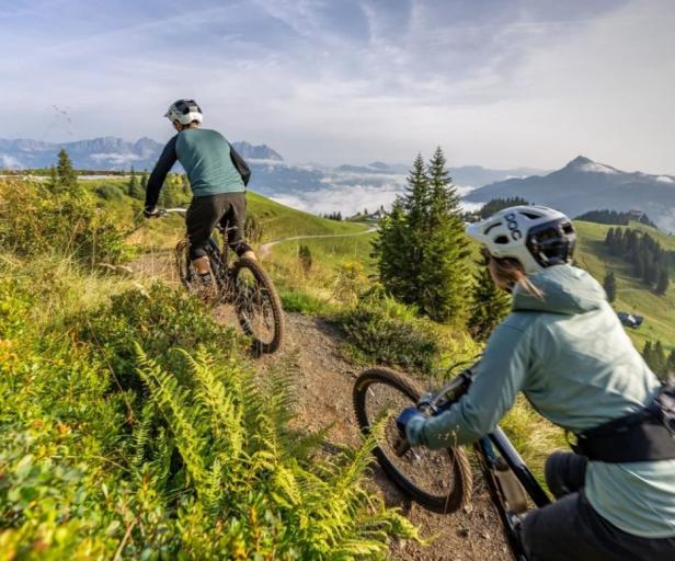 Zwei Mountainbiker fahren einen Trail in den Bergen hinunter.