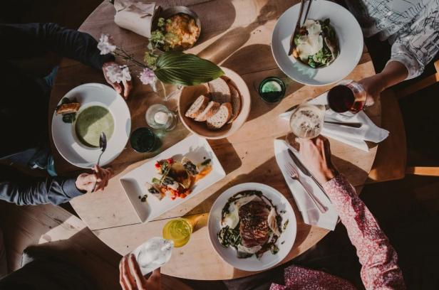 Menschen sitzen an einem Tisch und genießen gemeinsam Essen und Getränke.