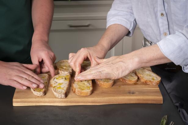 Zwei Personen richten Brotstücke auf einem Brett an.