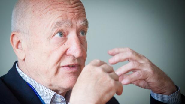 Ein älterer Mann mit hellblauen Augen gestikuliert mit seinen Händen.