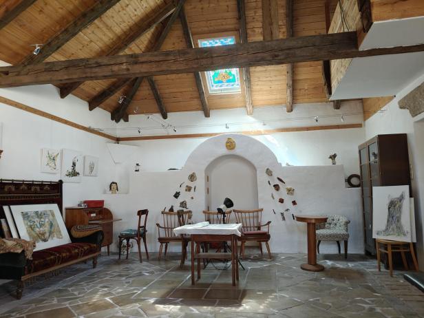 Ein Atelier mit Holzbalkendecke, Oberlicht und verschiedenen Kunstwerken, darunter eine Skulptur von Manfred Pawlik.