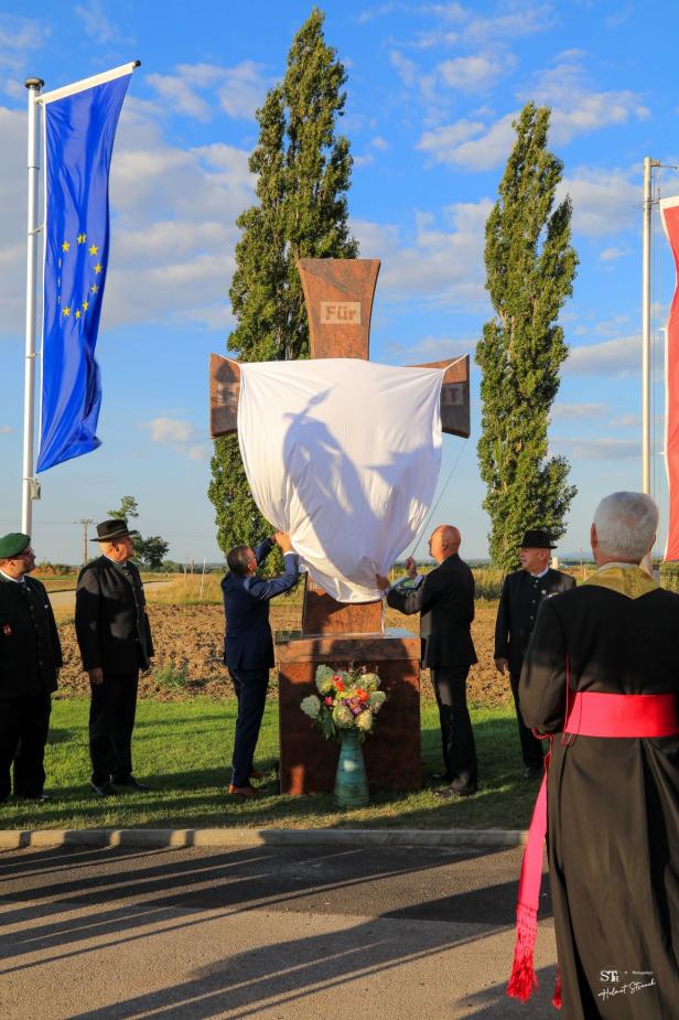 Enthüllung eines Kreuzes mit der Aufschrift „Für“ im Rahmen einer Feier.