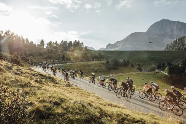 Eine Gruppe von Radfahrern fährt eine kurvenreiche Straße in den Bergen hinauf.