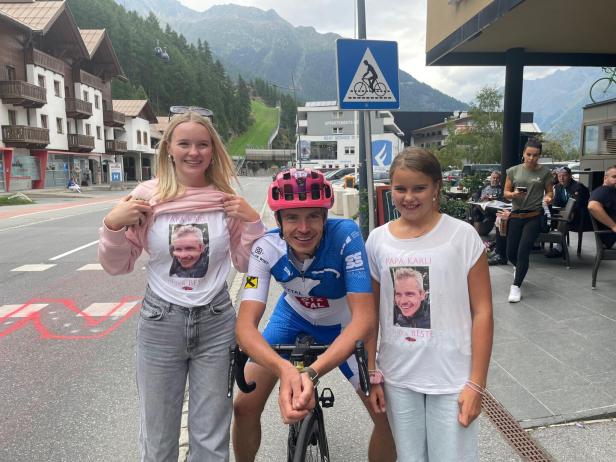 Ein Radfahrer posiert mit zwei jungen Frauen, die T-Shirts mit dem Aufdruck „Papa Karli ist der Beste“ tragen.