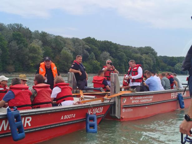 Eine Gruppe von Personen in Rettungswesten auf zwei Feuerwehrbooten auf dem Wasser.