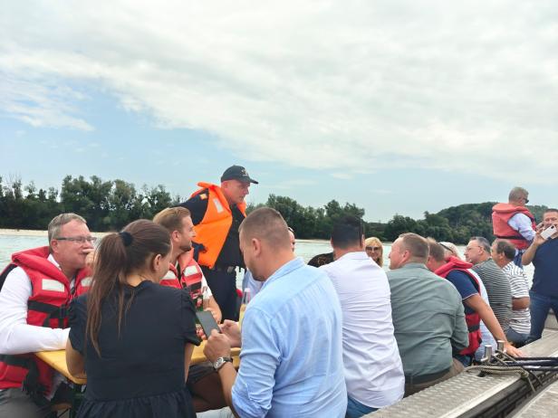 Eine Gruppe von Menschen sitzt mit Schwimmwesten auf einem Boot auf der March zwischen Marchfeld und der Slowakei.