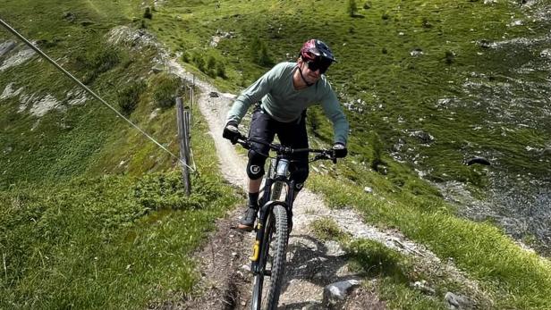 Ein Mann fährt auf einem Mountainbike über einen Bergweg.