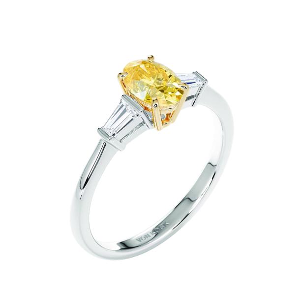 Ein Ring mit einem gelben Diamanten im Ovalschliff und zwei weißen Diamanten.