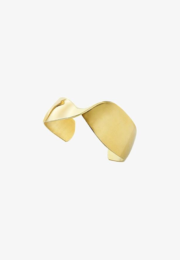 Ein goldener Armreif mit einer geschwungenen Form vor einem weißen Hintergrund.