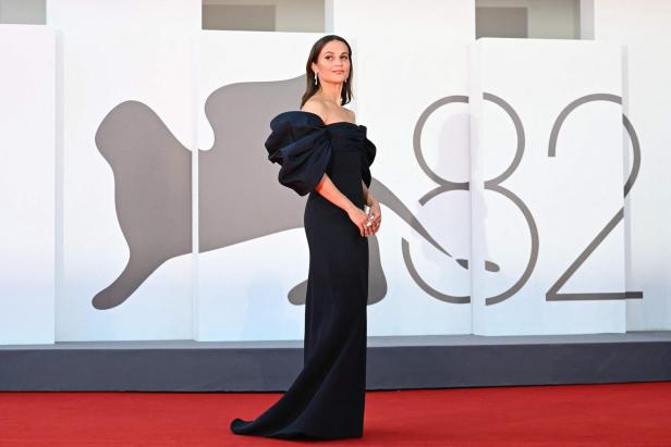 Eine Frau in einem schwarzen Kleid auf dem roten Teppich der Filmfestspiele von Venedig.