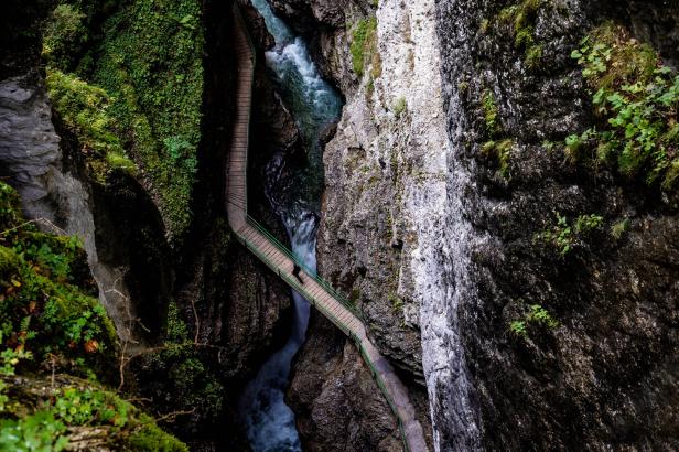 Eine Person überquert eine Schlucht auf einem schmalen Steg.