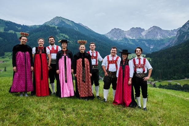 Eine Gruppe von Menschen in traditioneller Tracht vor einer Bergkulisse.