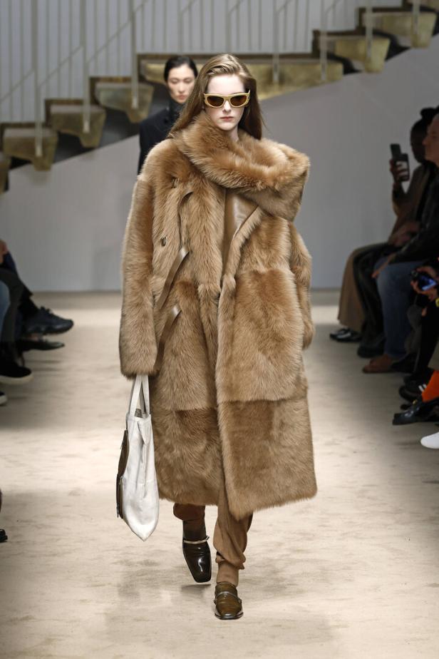 Ein Model präsentiert einen übergroßen Pelzmantel und eine Handtasche auf dem Laufsteg von Tods Herbst/Winter 2025/26.