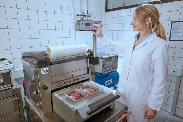 Eine Frau im Laborkittel verpackt Lebensmittel mit einer Schutzgasverpackung.