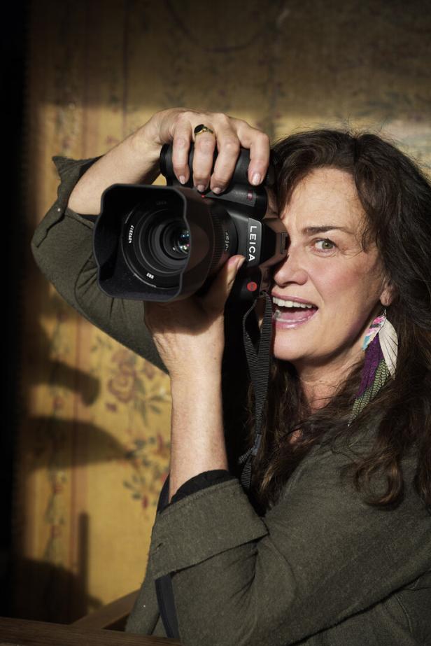 Eine Frau mittleren Alters fotografiert mit einer Leica-Kamera.