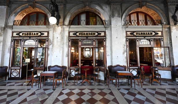 Das historische Café Florian in Venedig mit Tischen und Stühlen vor dem Eingang.
