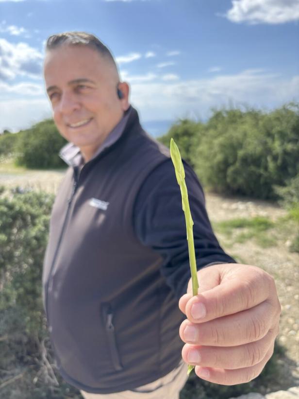 Mann hält Wildspargel in die Kamera.