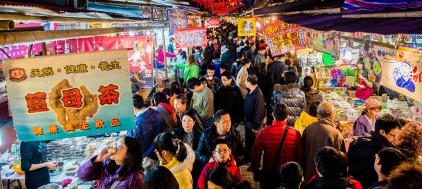 Ein belebter Nachtmarkt in Taipeh mit vielen Menschen und Verkaufsständen.