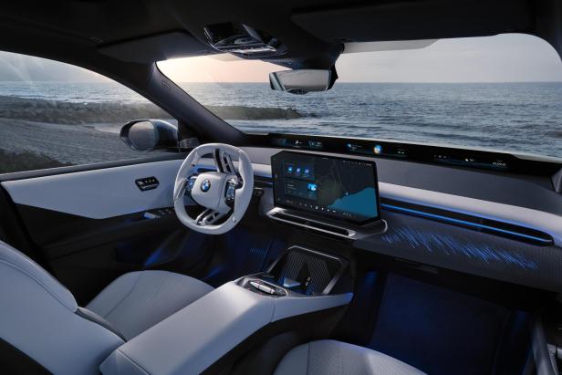 Der neue blaue BMW iX3 von innen, mit hellem Lenkrad und einem großen Bildschirm.