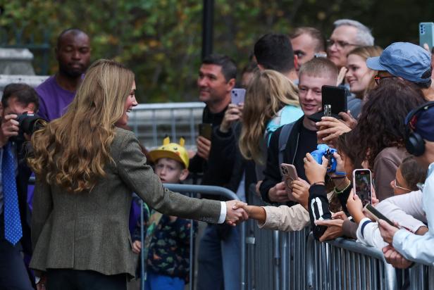 Prinzessin Kate schüttelt Hände Prinzessin Kate im Blazer schüttelt die Hand eines Kindes, während umstehende Menschen Fotos machen.
