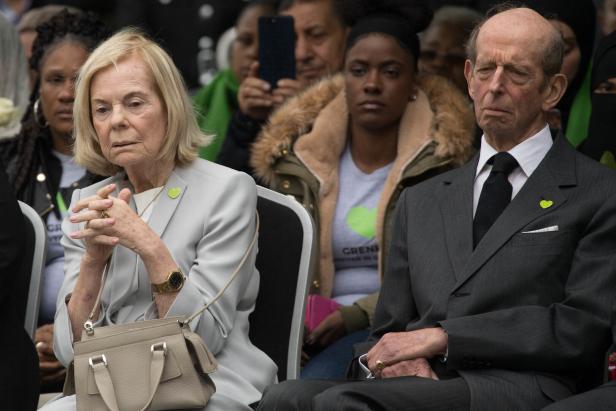 Der Herzog und die Herzogin von Kent sitzen formell gekleidet in einer Menschenmenge, beide tragen grüne Herz-Anstecker.