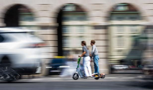 Zwei Menschen fahren auf einem E-Scooter
