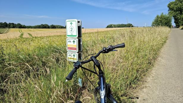 Ein Fahrrad steht an einem Wegweiser für Radrouten in Flandern.