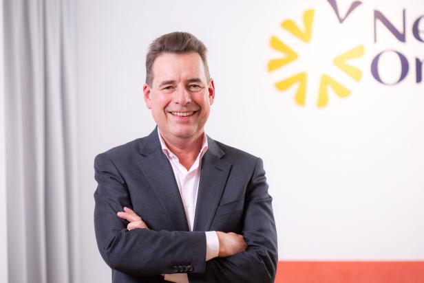 Matthias Krön, CEO und Mitbegründer der „New Originals Company“ steht mit verschränkten Armen vor einer gräulichen Wand.