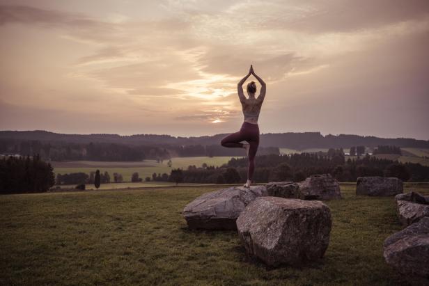 Eine Frau macht Yoga in der Natur, beim Falkensteiner Hotel Bad Leonfelden.