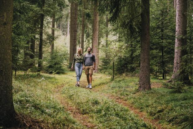 Ein Paar geht im Wald spazieren, beim Falkensteiner Hotel Bad Leonfelden.