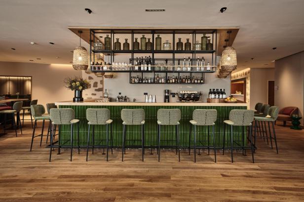 Eine schicke, grüne Bar mit viel Holz und indirektem Licht im Falkensteiner Hotel Bad Leonfelden.