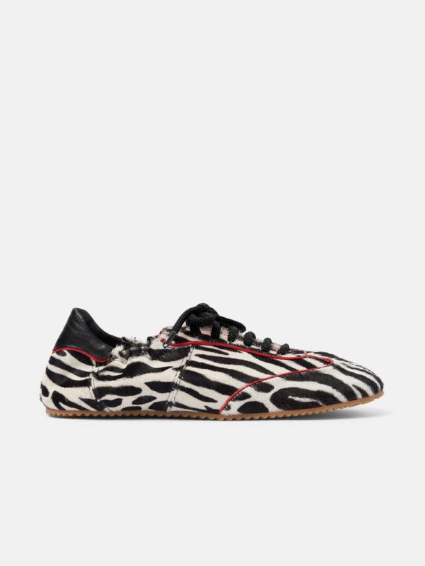 Ein Sportschuh mit Zebramuster und roten Akzenten steht auf einem weißen Hintergrund.