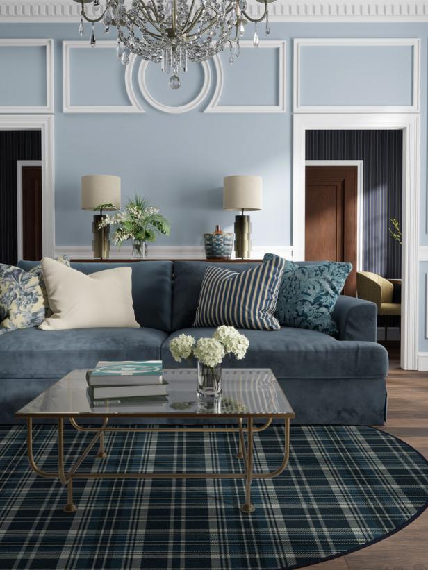 Ein Wohnzimmer in Blautönen mit einem Sofa, einem Couchtisch und einem Kronleuchter.
