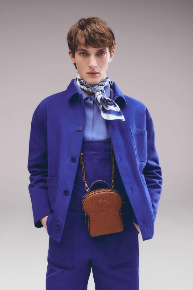Ein Mann in einem blauen Outfit trägt eine braune Tasche in Form einer Toastbrotscheibe.