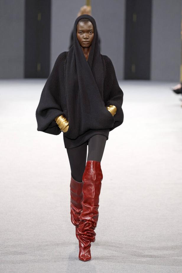Ein Model in einem schwarzen Kapuzenpullover und roten Stiefeln auf dem Laufsteg der Balmain Studios Herbst/Winter 2025/26 in Paris.