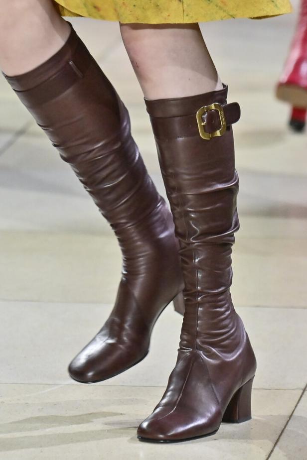 Braune Lederstiefel mit goldenen Schnallen auf einem Laufsteg von Miu Miu.