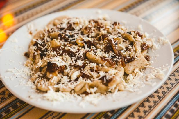 Ein Teller mit Makarounes, garniert mit Käse und karamellisierten Zwiebeln.