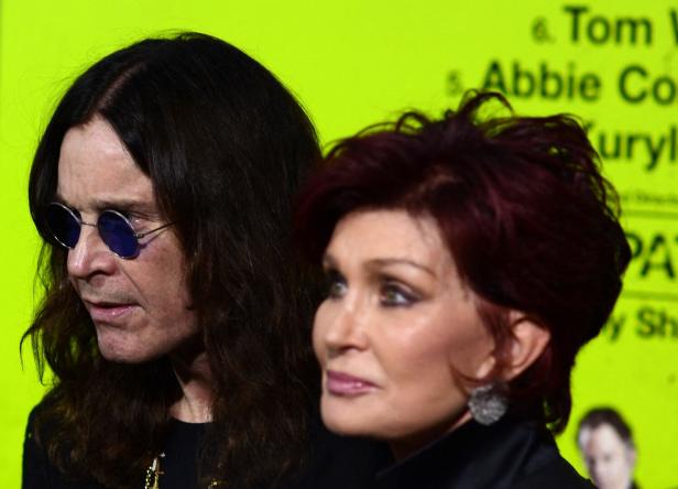 Ozzy und Sharon Osbourne posieren vor einem hellgrünen Hintergrund.