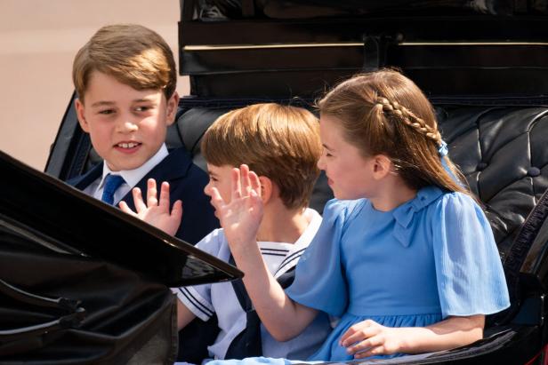 Prinzessin Charlotte mit ihren Brüdern George und Louis (2022) Prinz George, Prinz Louis und Prinzessin Charlotte winken aus einer Kutsche.