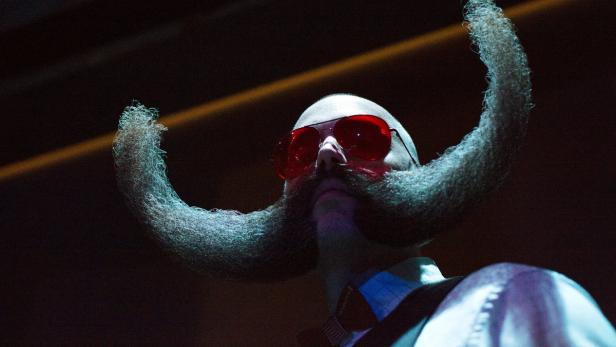 Ein Mann mit roter Sonnenbrille und einem extravaganten Bart, der nach oben gebogen ist.