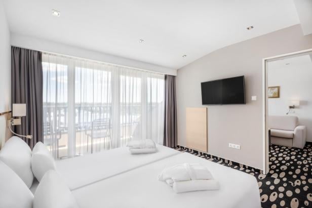 Hotelzimmer mit großem Bett und Fernseher, gemütlich und modern eingerichtet.