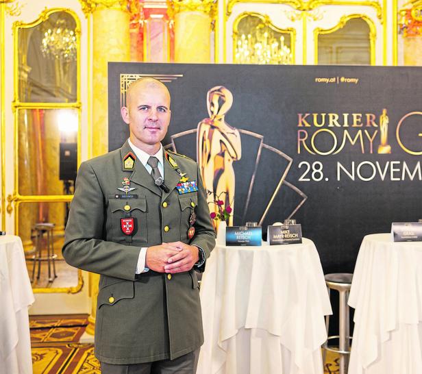 Ein Mann in Uniform steht vor einem „Kurier Romy“-Banner. Ein Mann in Uniform steht vor einem „Kurier Romy“-Banner.